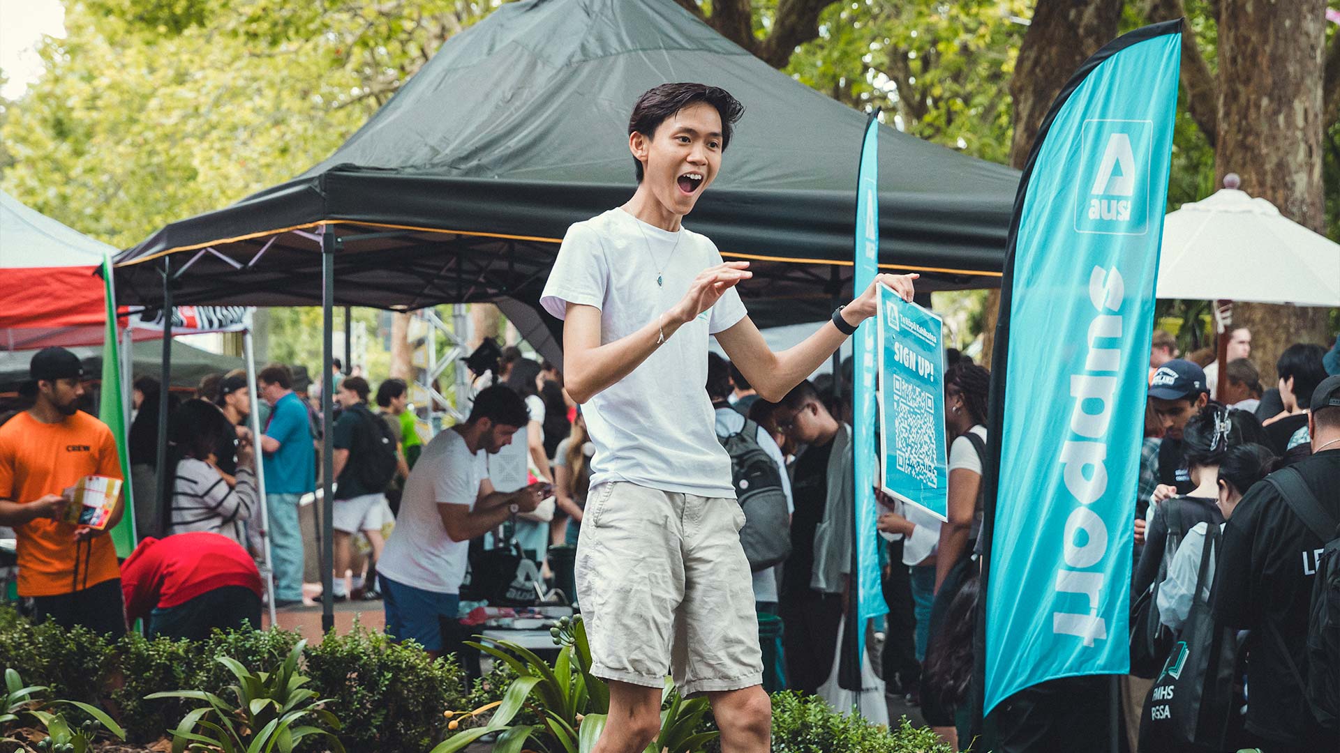 A student advertising their event on campus with a blue poster with a QR code
