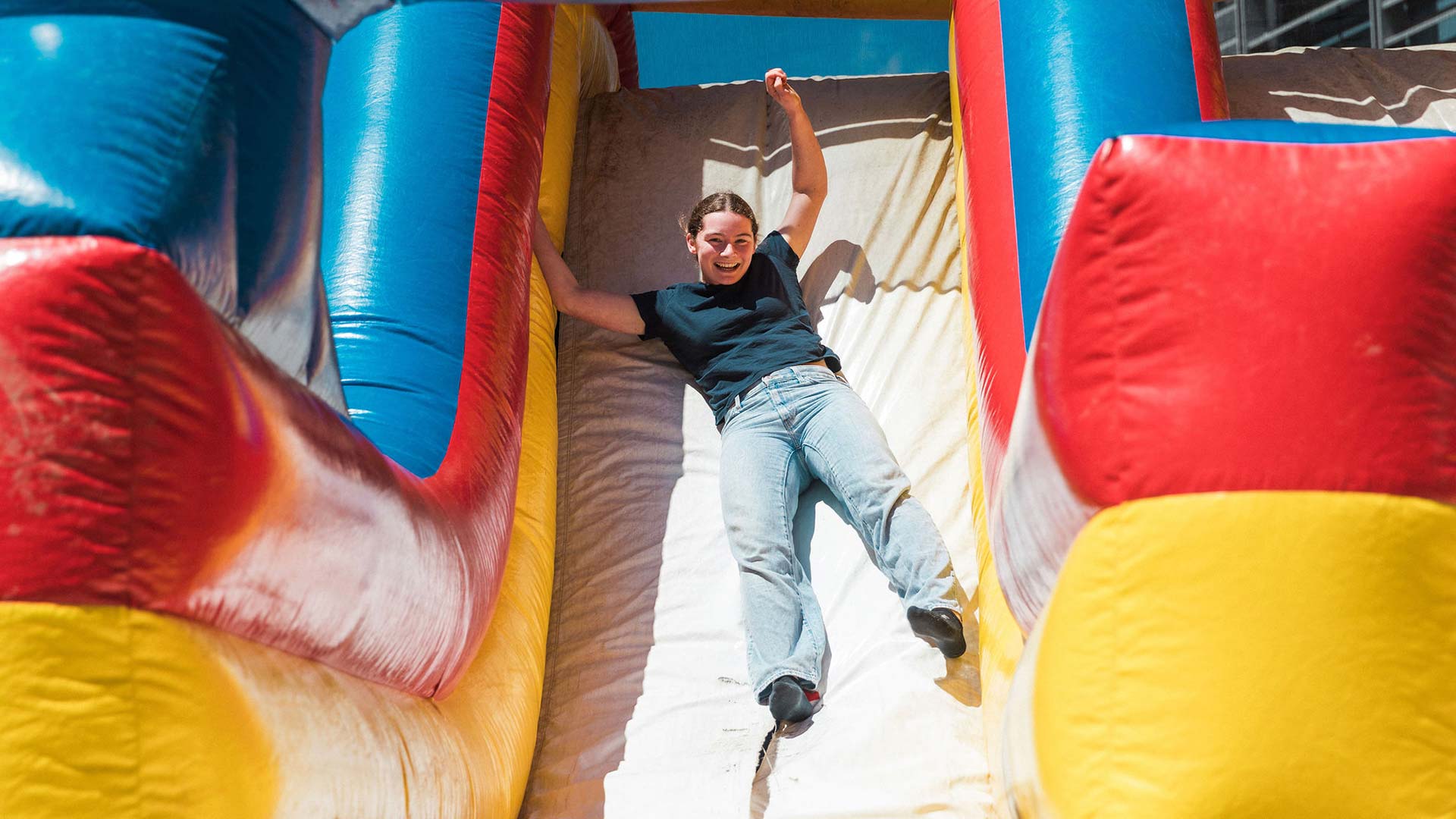 A person laughing and sliding down an inflatable slide on a bouncy castle